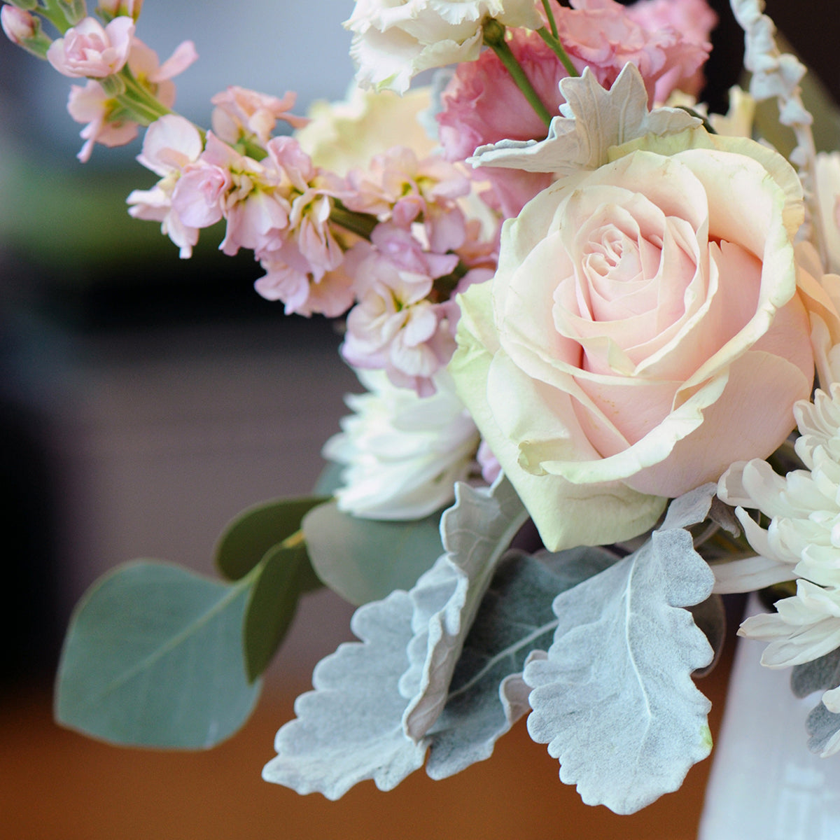 Close-up of a bouquet with pink and white flowers and green leaves.
