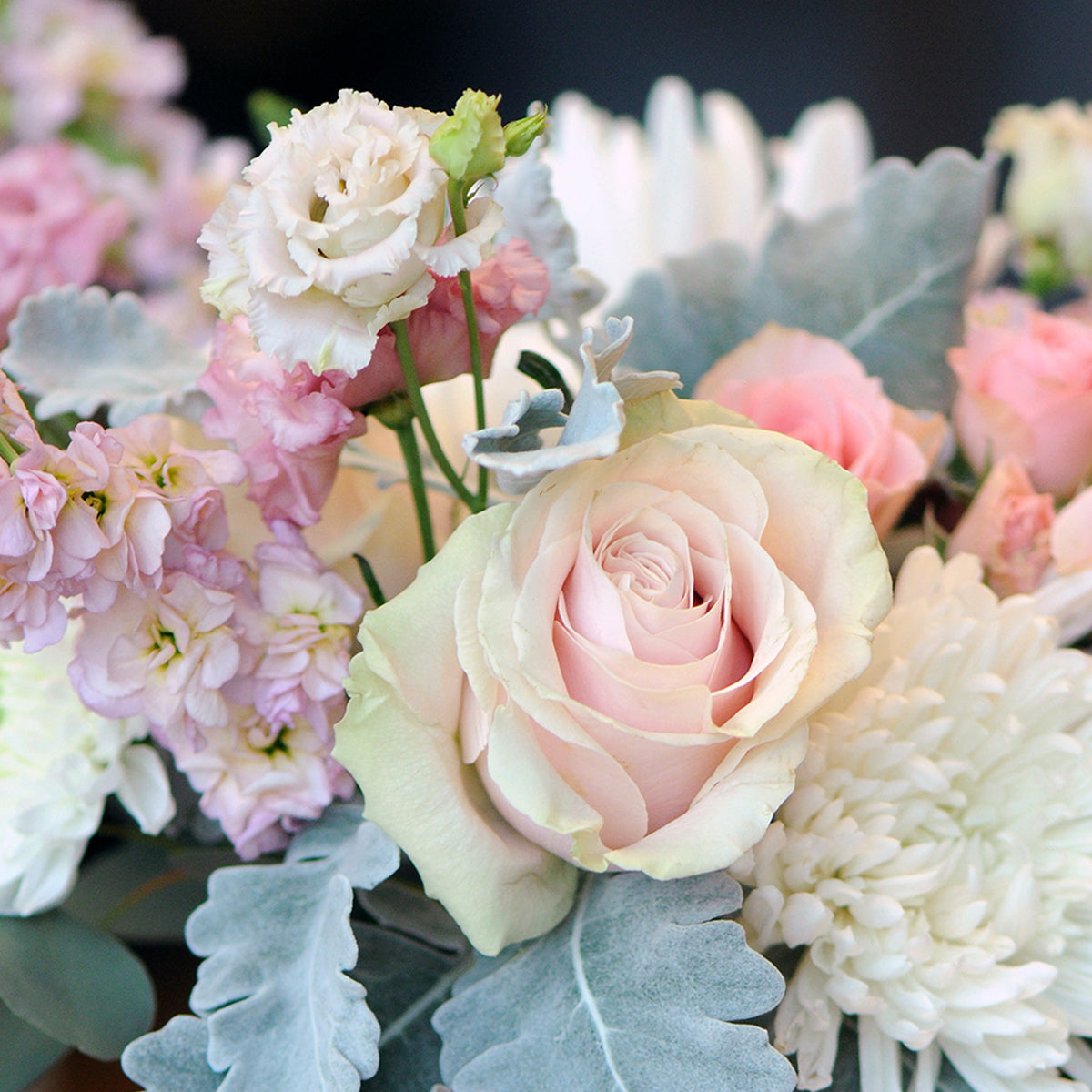 Close-up of a bouquet of flowers with pink and white roses and greenery.