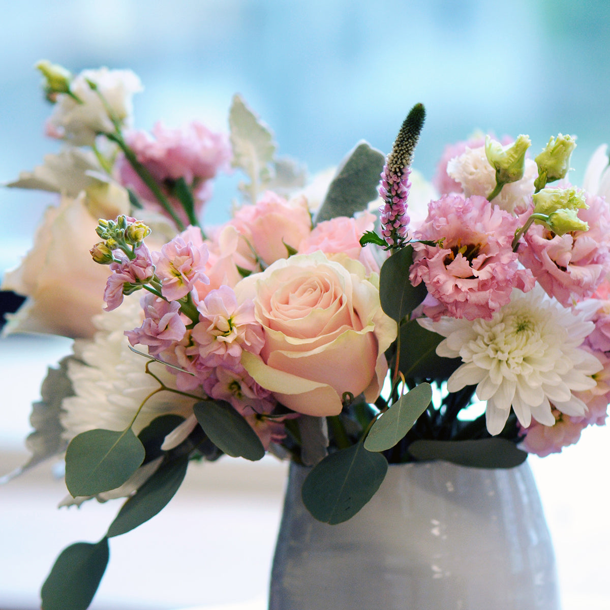 Bouquet of pink and white flowers in a white vase with a blurred background