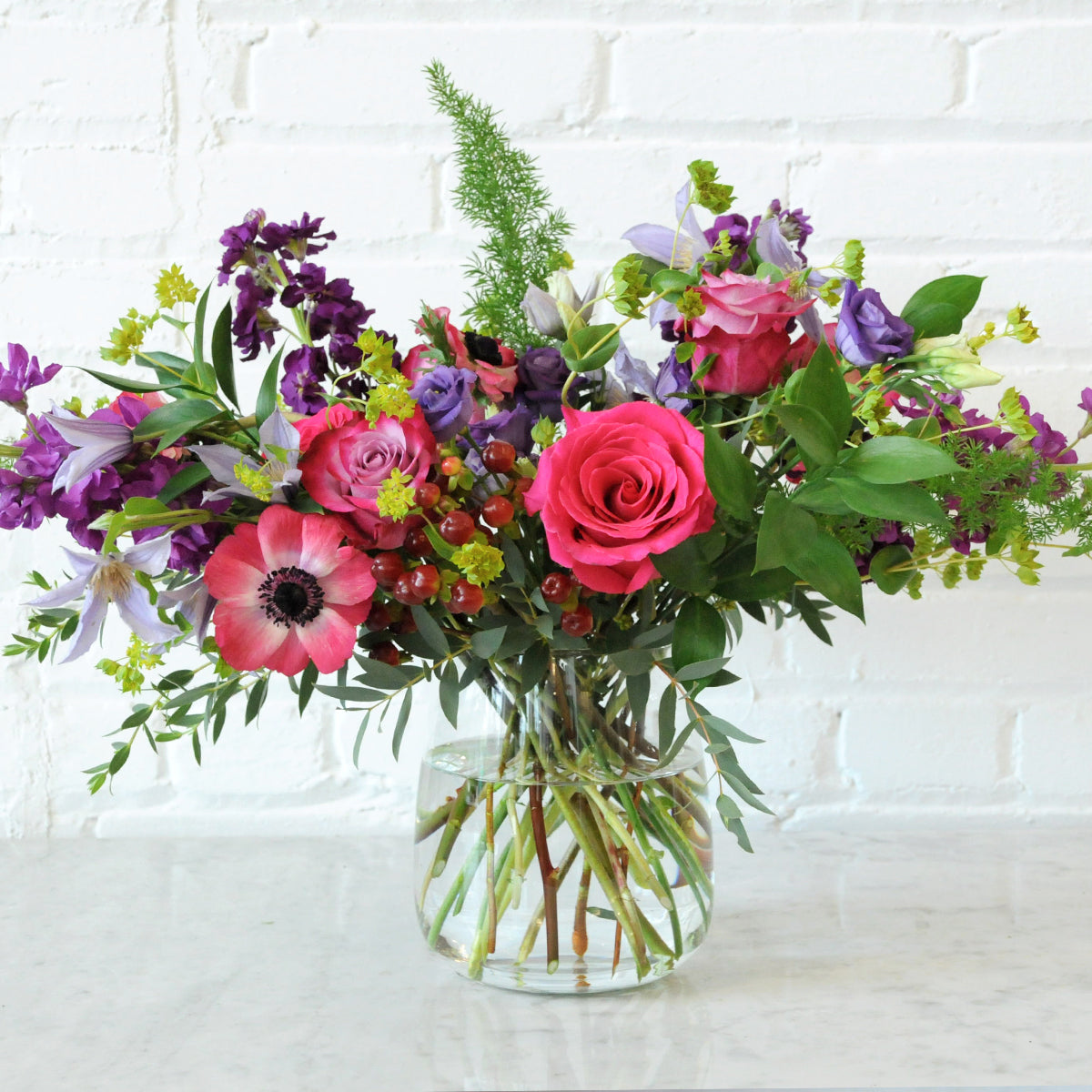Spruce Flowers Floral arrangement arranged in clear kettle vase with Pink Roses