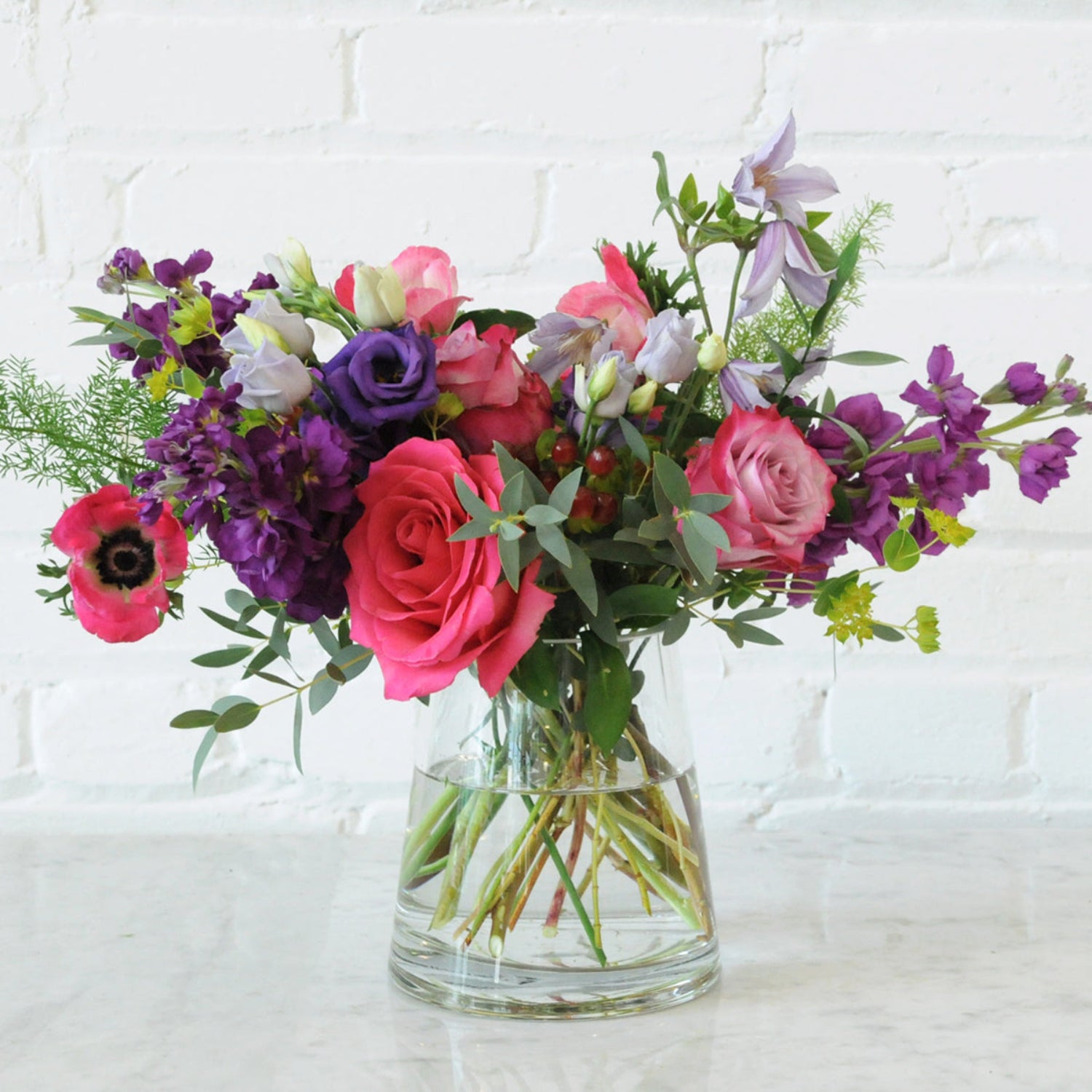 Spruce Flowers Aldrich arrangement with Pink roses Lisianthus textural foliage set in a pyramid clear glass vase