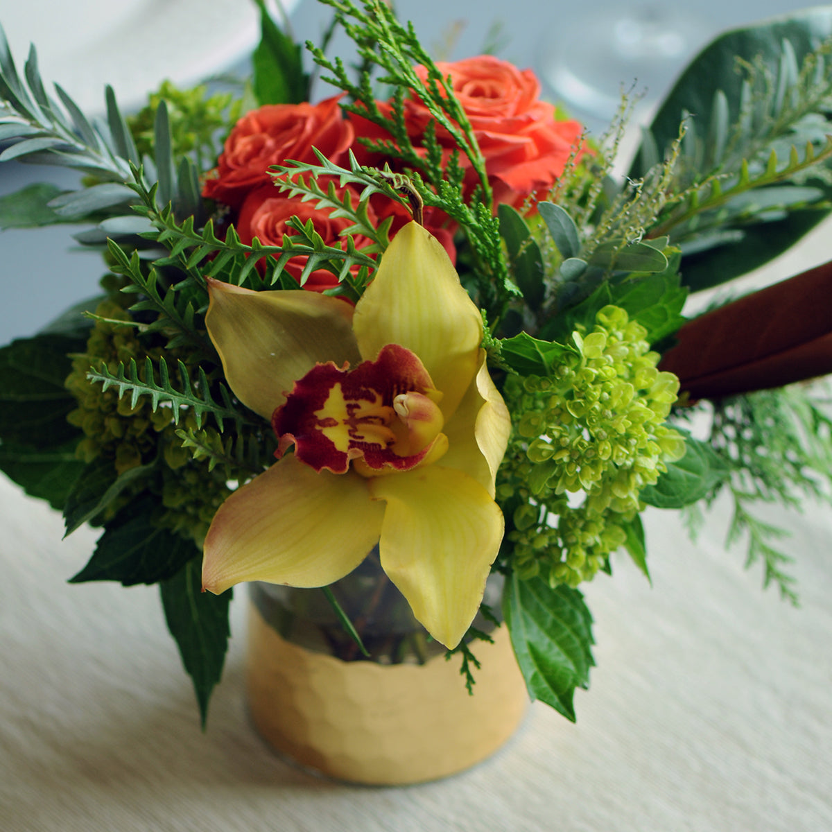 Bouquet of flowers with a yellow orchid in a vase on a light surface