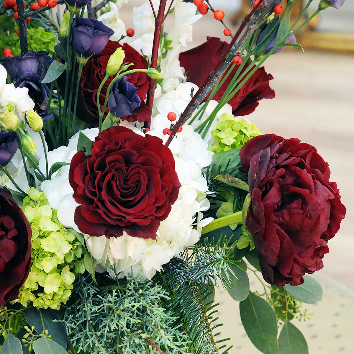 Bouquet of red, white, and green flowers with berries on a blurred background