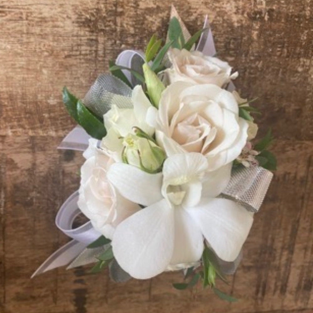 Floral corsage with white and beige flowers on a wooden surface