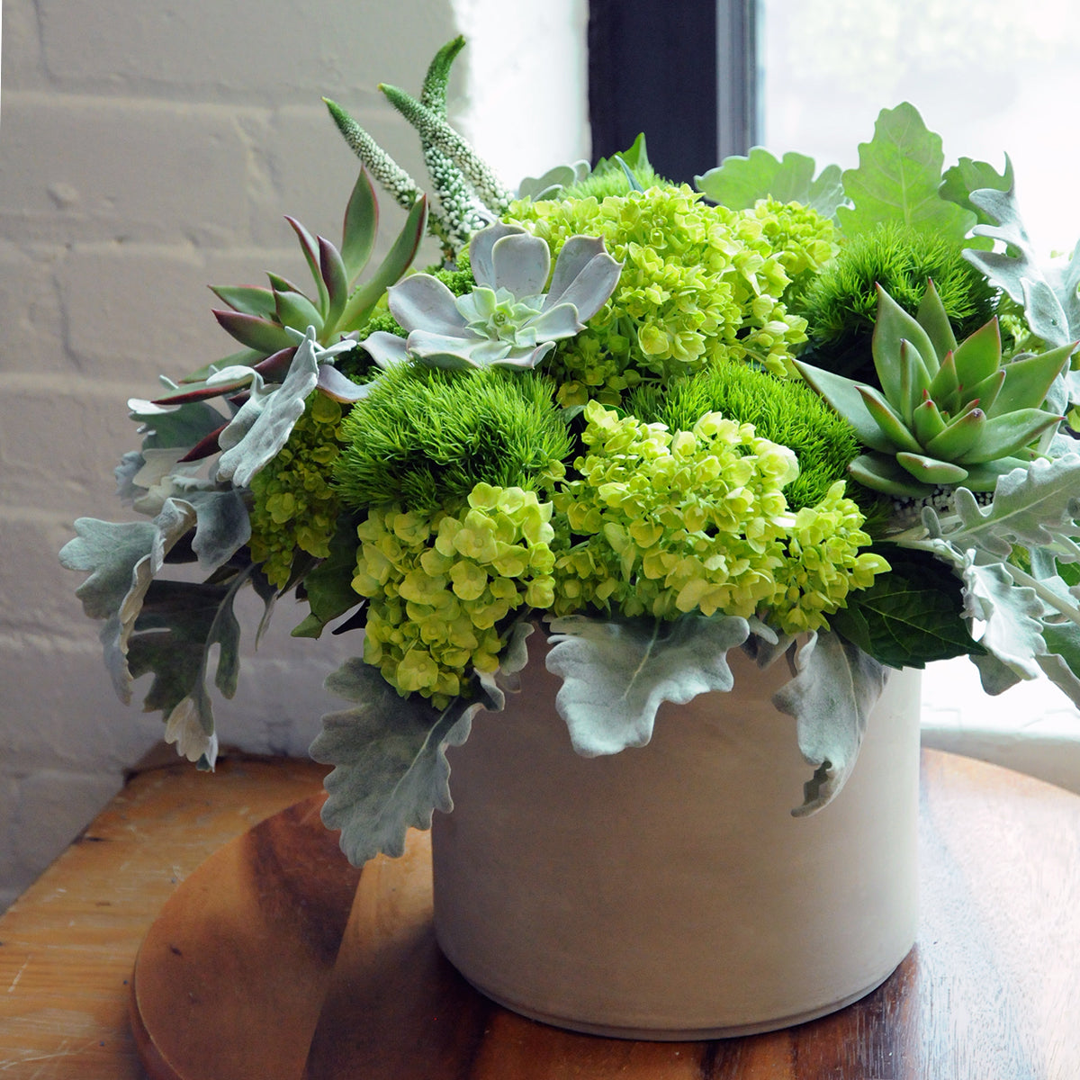 Floral arrangement  with green succulents and flowers on a wooden surface