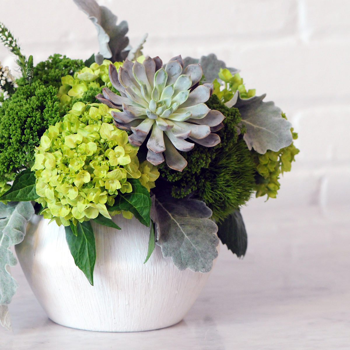 Bouquet of green and purple flowers in a white vase on a light background