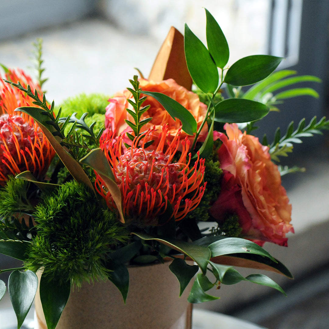 Close up image of flowers of floral arrangement showing Red Protea and Roses