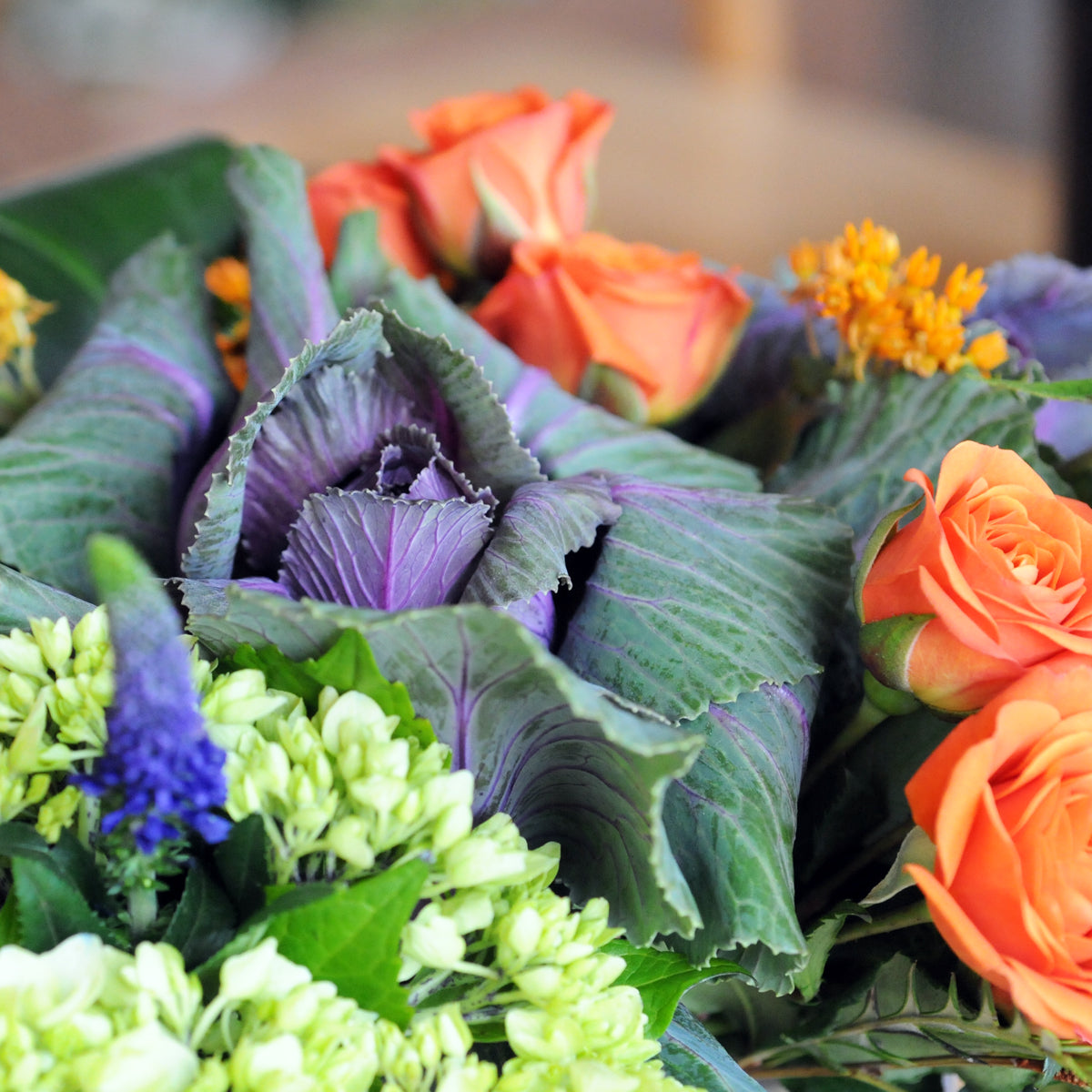 Our Bryant floral arrangement is a Spruce Flowers classic that features Spray roses with Mini Greens, Kale, Aspidistra leaf roll and Veronica all displayed in a Cube vase.