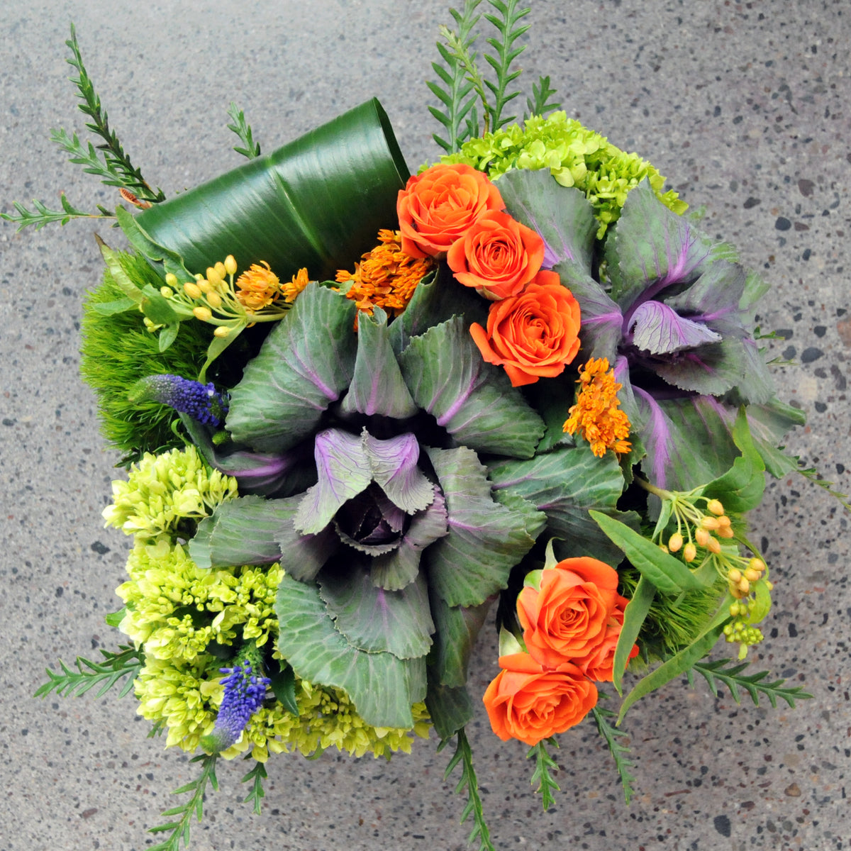 Top doen view of Spruce Flowers Bryant arrangement featuring Kale Acelepias Sray roses and foliage  