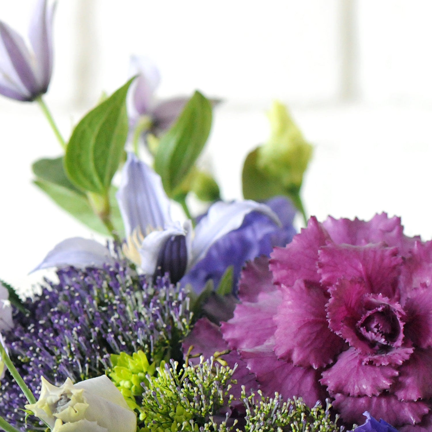 Close up detail image of Clematis blooms and Kale. Image is an example of the styling rather than the exact arrangement that will be sent
