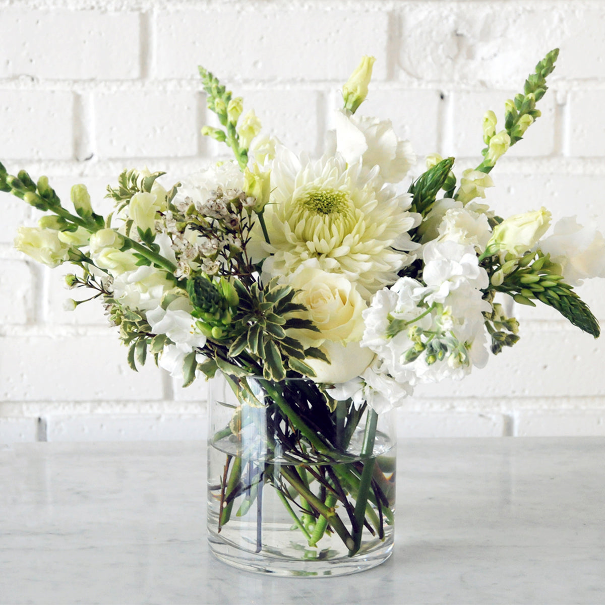 Image of a whimsical floral arrangement in white arranged in a glass vase.