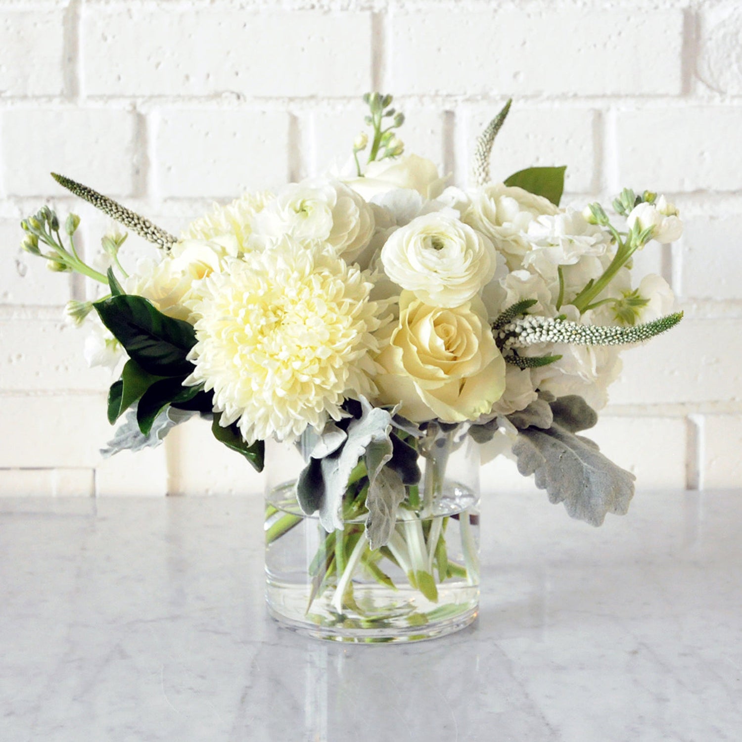 Spruce Flowers como arrangement of white florals shown in a glass vase