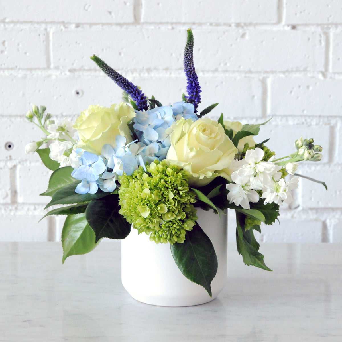 Spruce Flowers James arrangement in a white Kendal vase with Blue Hydrangea white Roses and Stock