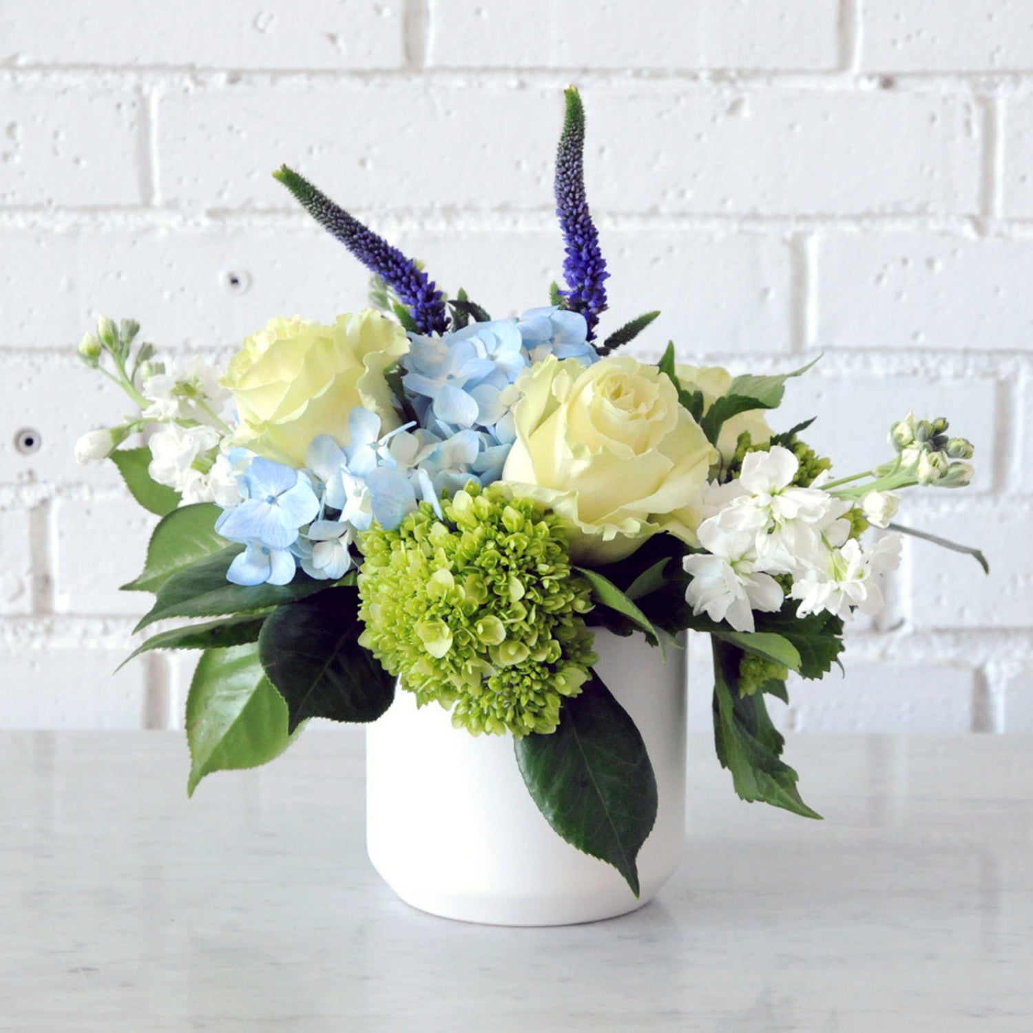 Spruce Flowers James arrangement in a white Kendal vase with Blue Hydrangea white Roses and Stock