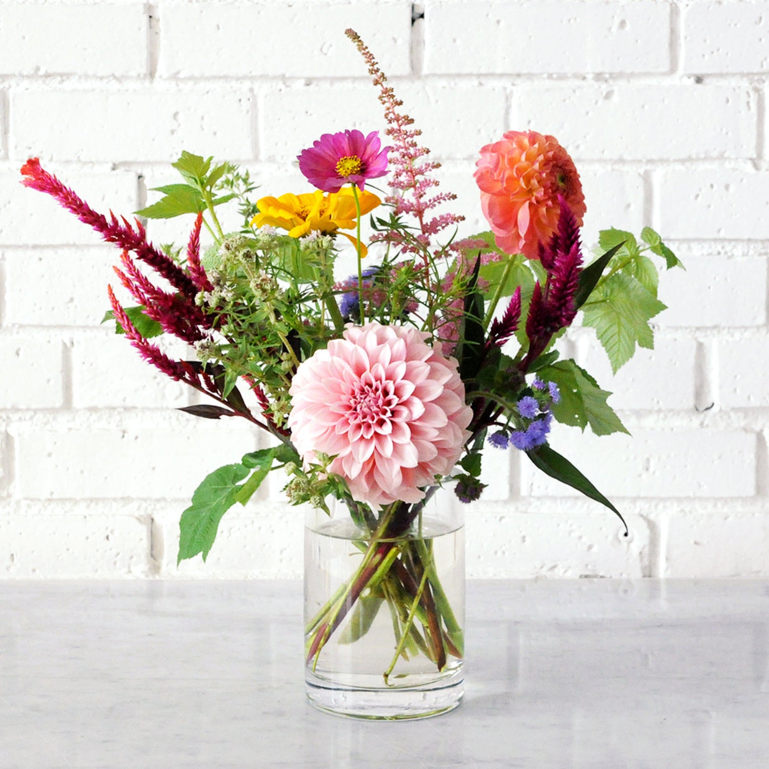 An example of the Larpenteur arrangement featuring dahlias in a tall glass cylinder vase