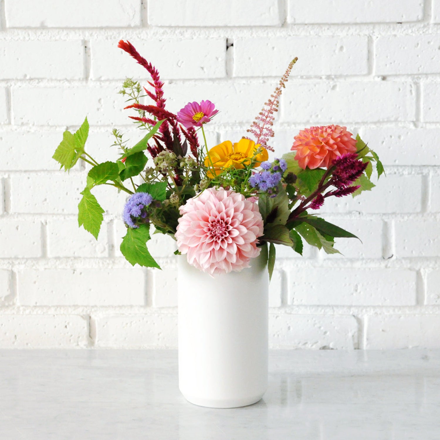 An example of the Larpenteur arrangement featuring dahlias in a tall white ceramic vase