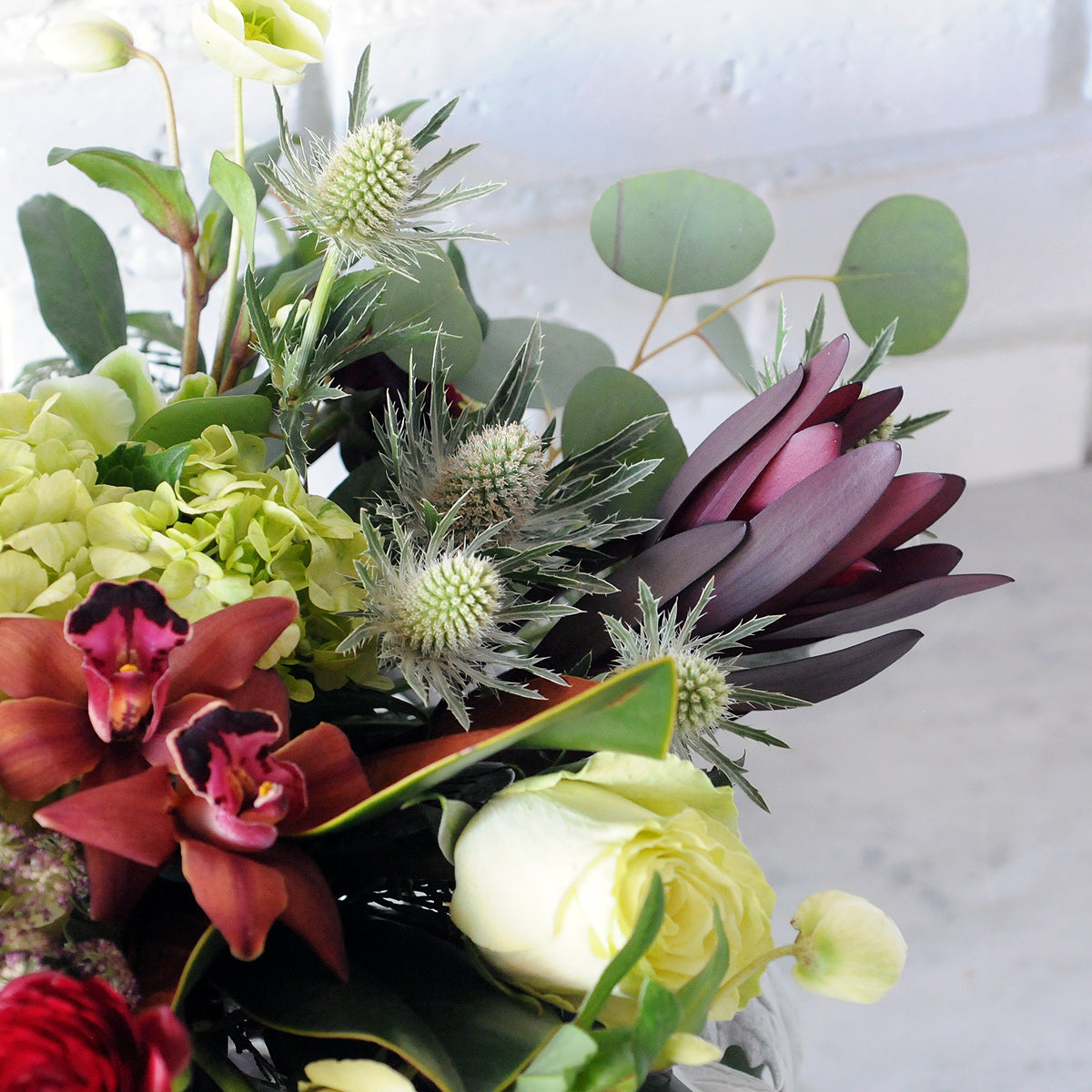 Close up view of Spruce Flowers Linden arrangement showing Thistle Orchids Hellebore blooms.