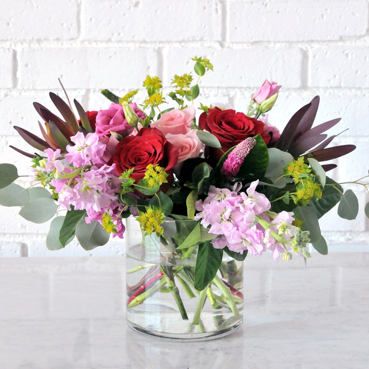 Studio shot of the Wabasha Flower arrangement by Spruce Flowers and Events Showing it pink and red floral tones 