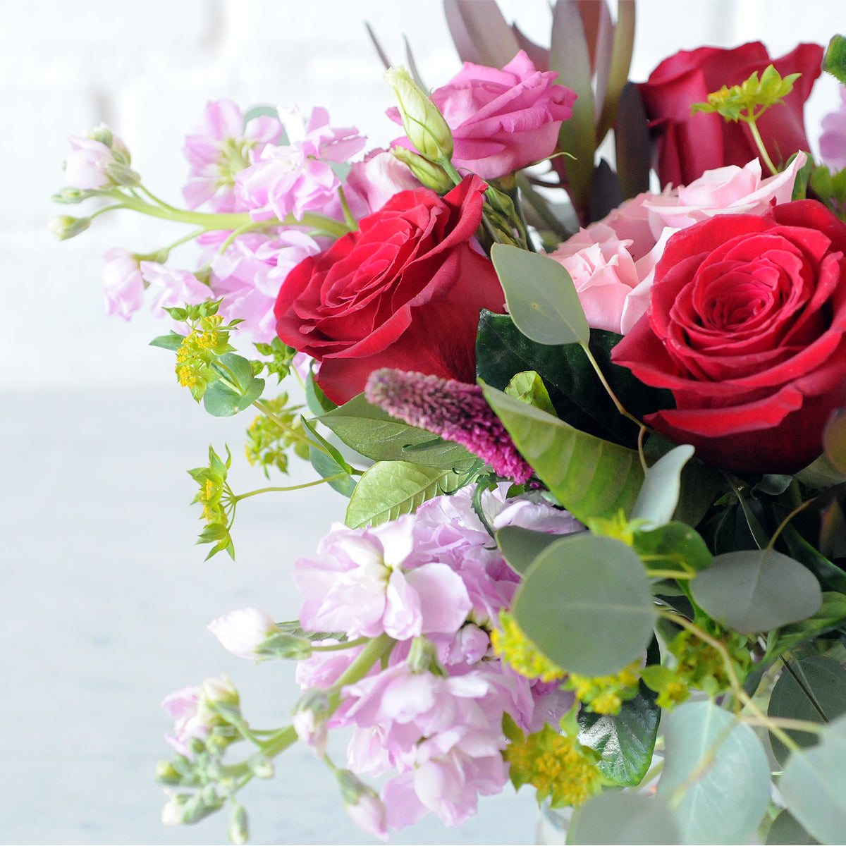 Close up of Wabasha Flower arrangement showing pink scented stock and Red Freedom roses in the arrangement