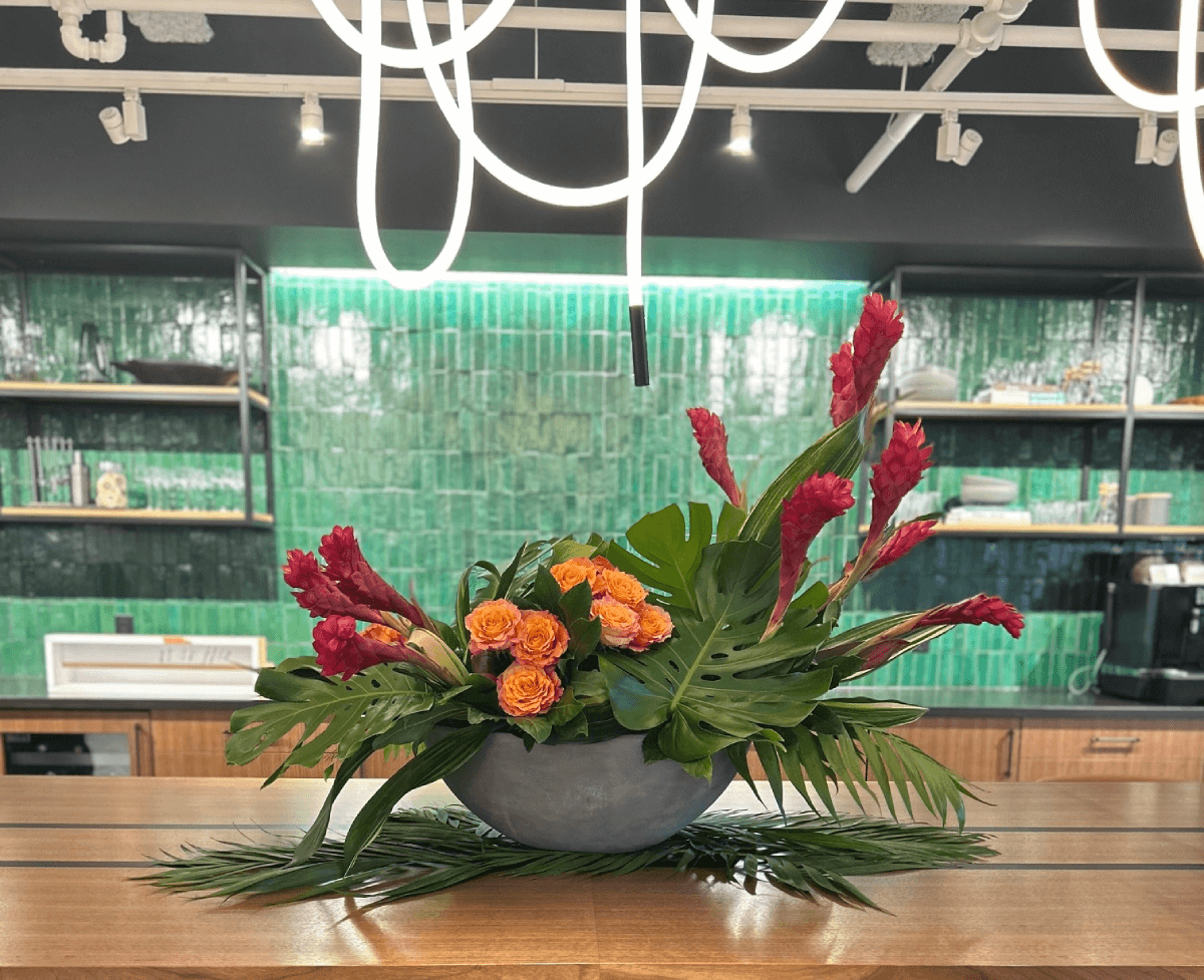 Large tropical flower arrangement in concrete boat shaped bowl ginger and tropical leaves  