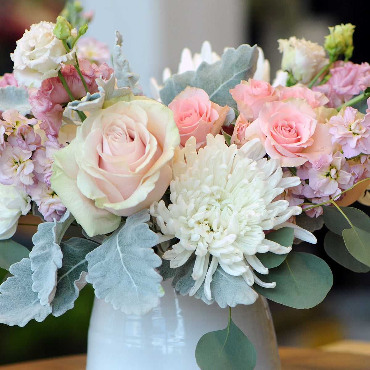 Bouquet of pink and white flowers in a white vase with a blurred background