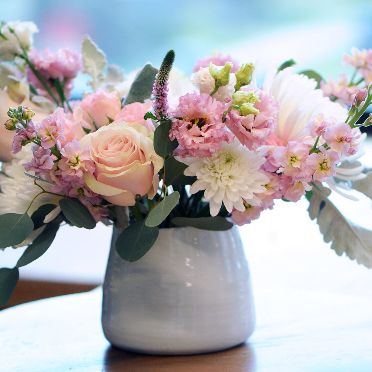 Bouquet of pink and white flowers in a white vase on a blurred background