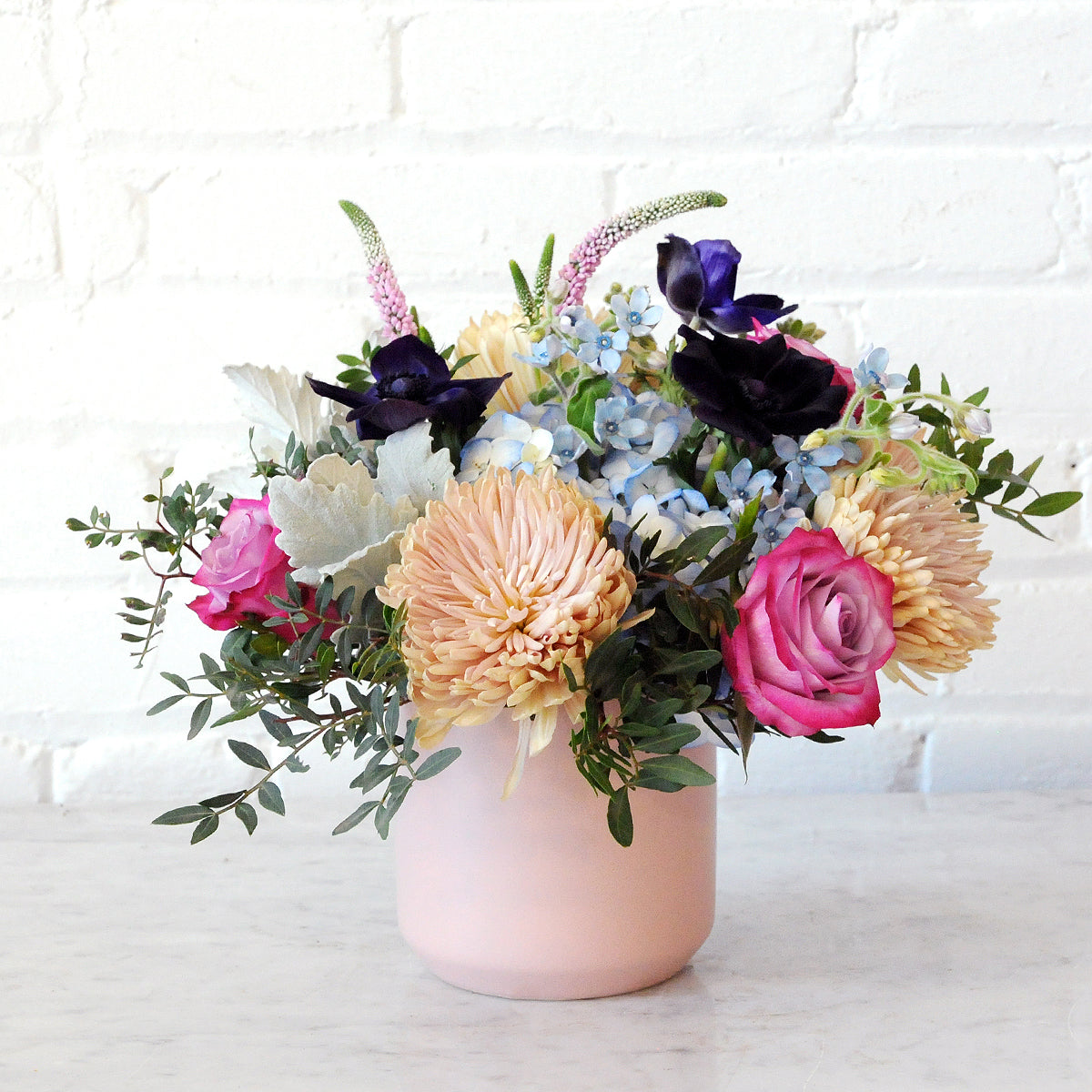 Spruce Flowers Emerson arrangement classical but with a hint of whimsy arranged in a soft pink ceramic vase 