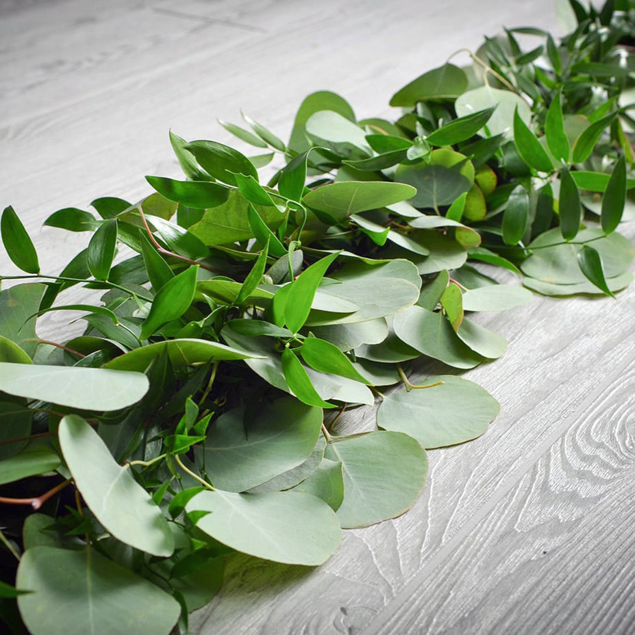 Green leaves on a light wooden surface
