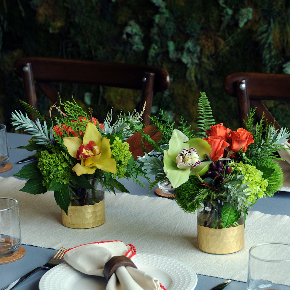 Decorative floral arrangements on a table with a greenery backdrop