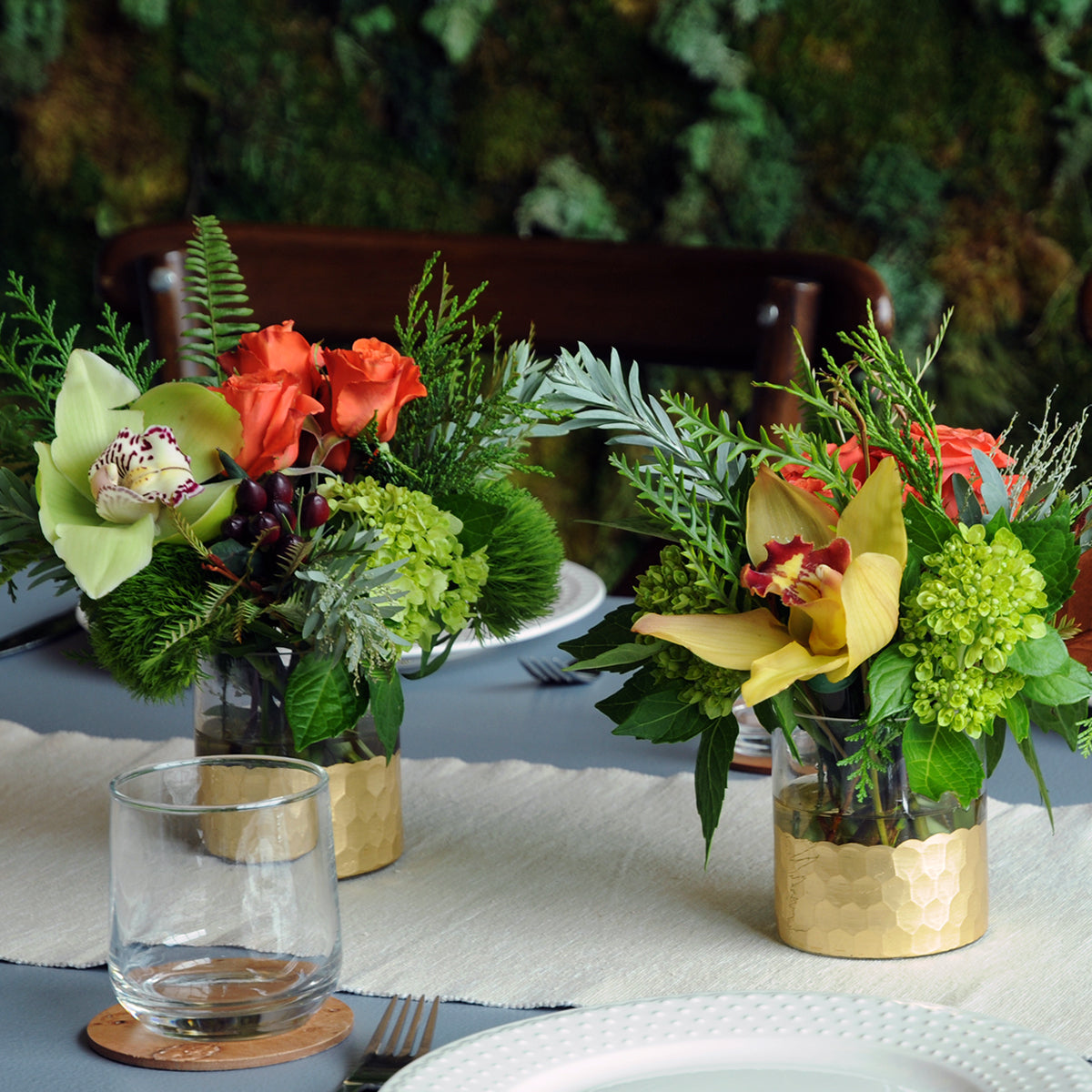Decorative table setting with floral arrangements and a glass on a tablecloth.