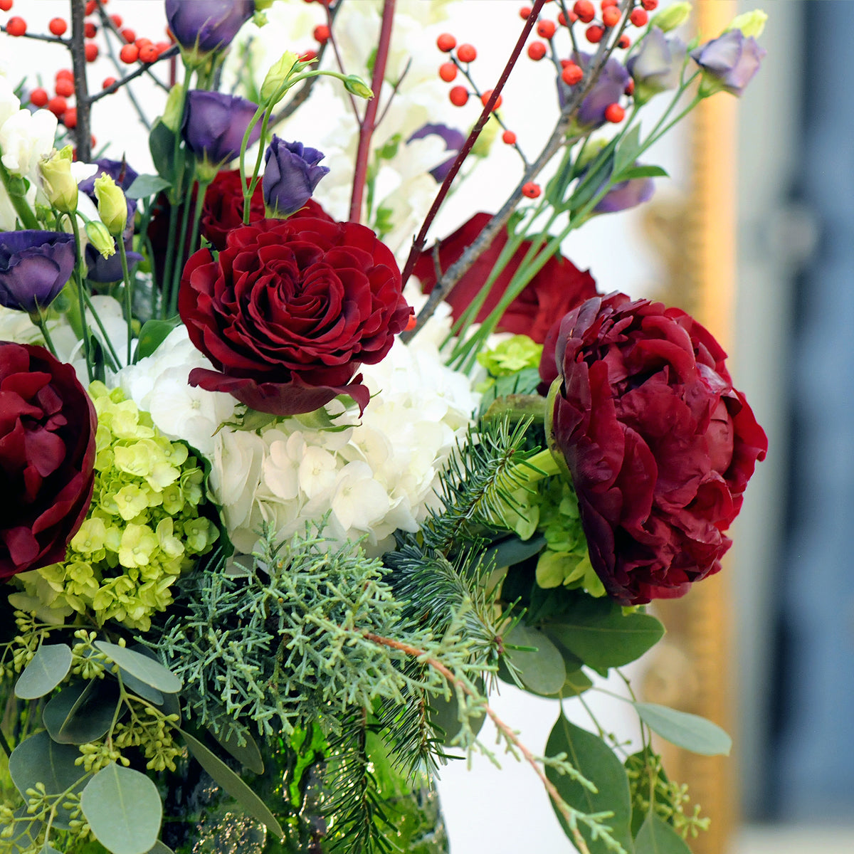 Bouquet of red roses, greenery, and other flowers with a blurred background