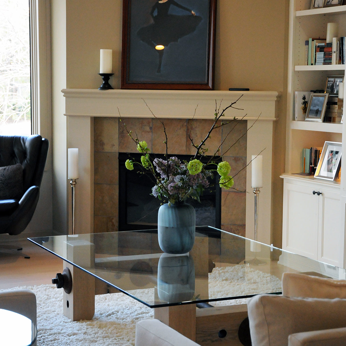 Living room with a fireplace, glass coffee table, and decorative items.
