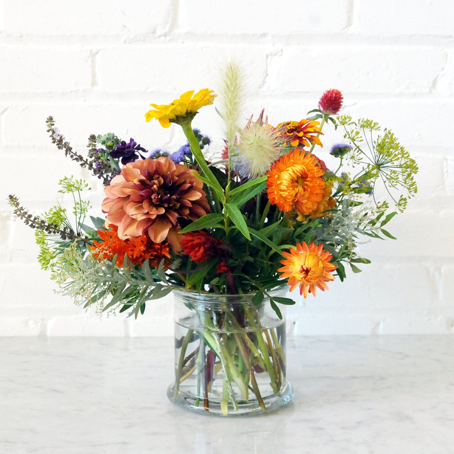 An example of the Larpenteur arrangement featuring dahlias in a cylinder clear glass vase