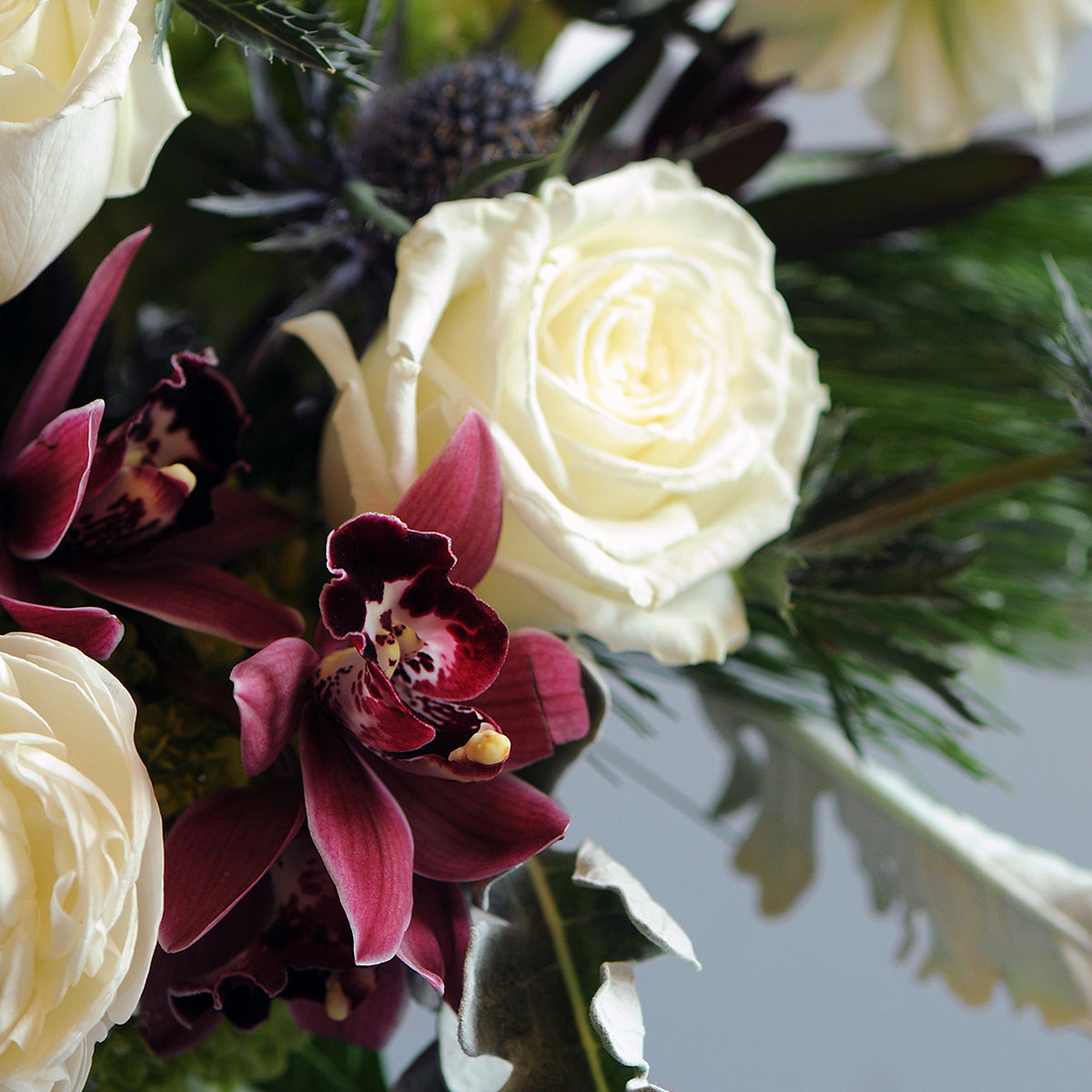 Bouquet of white roses and purple/pink  orchids with green leaves.
