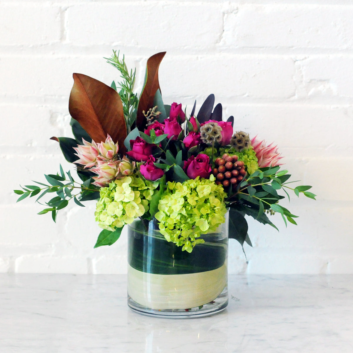 Floral arrangement in glass vase with leaf wrap 