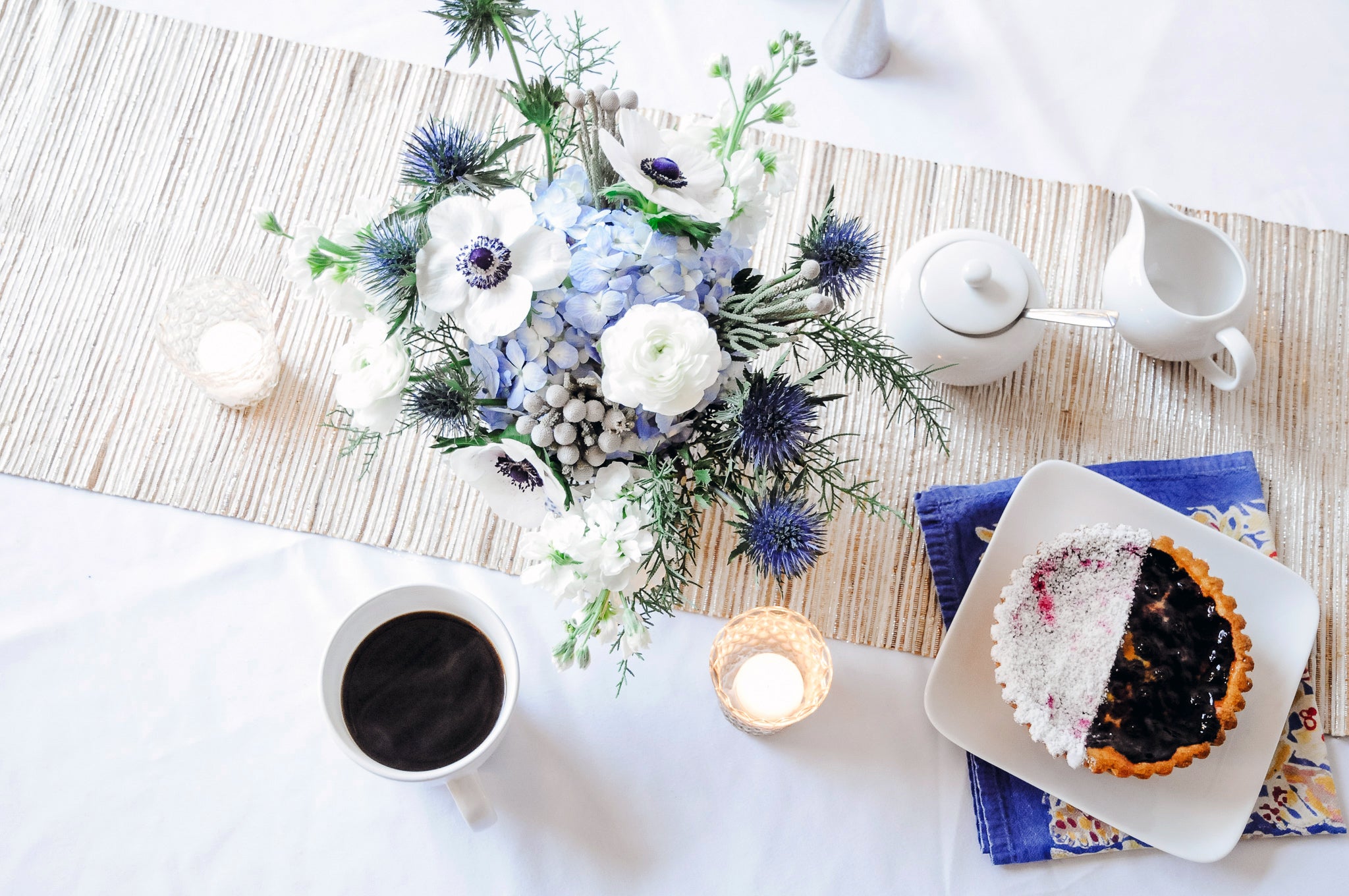 Freemont flower arrangement in subtle white blue tones shown on a table setting 