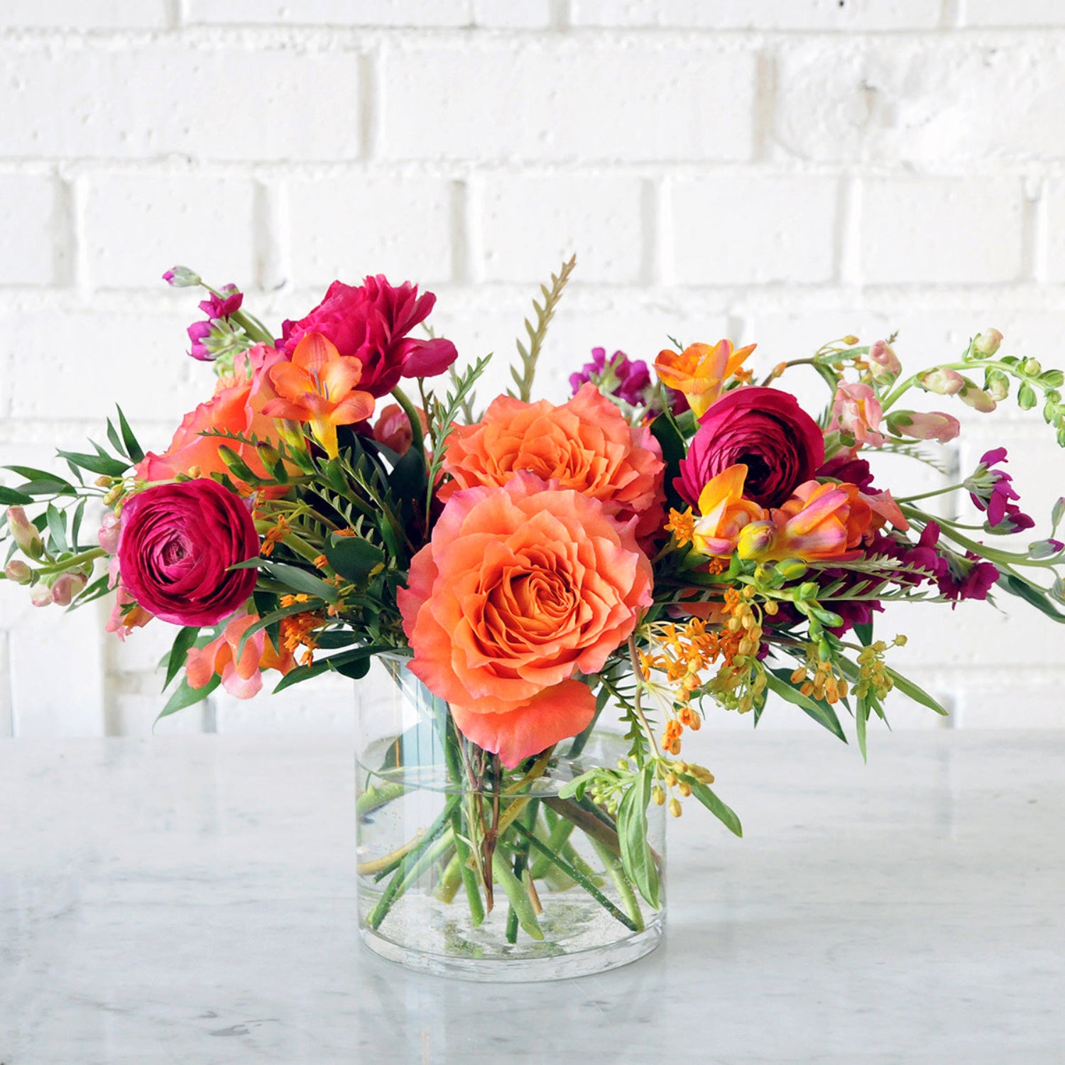 Bright Whimsical Floral arrangement with orange and jewel tones. Image is an example of the styling rather than the exact arrangement that will be sent 