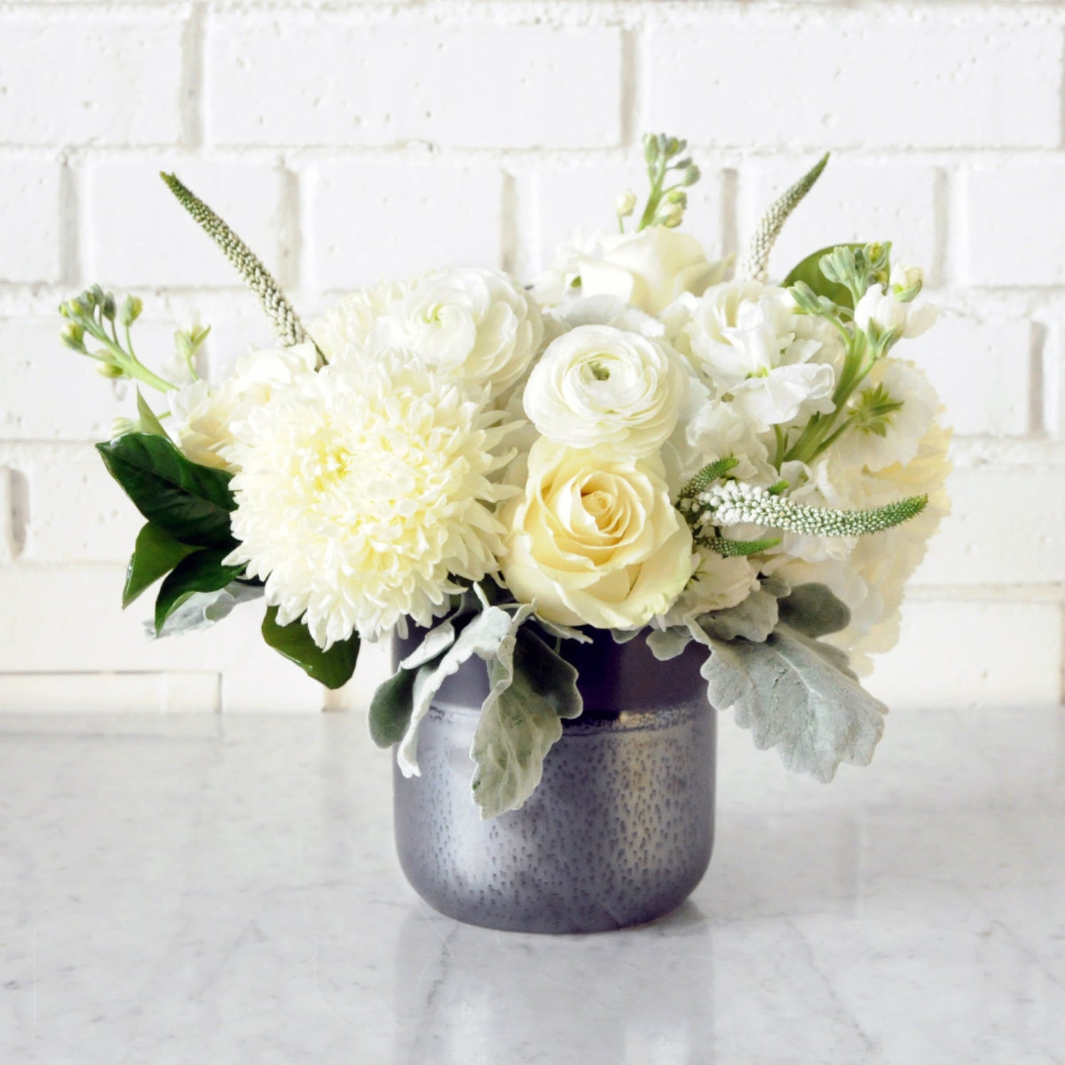 Spruce Flowers monochromatic white Como floral arrangement shown in a black and silver ceramic vase  